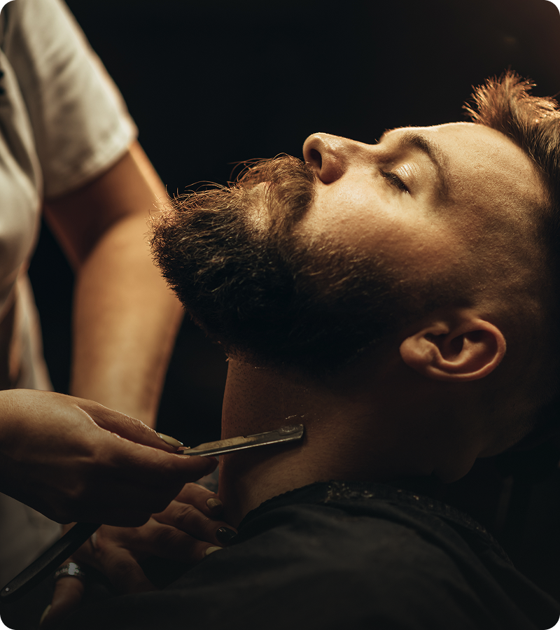 Barber shaving man's beard with razor